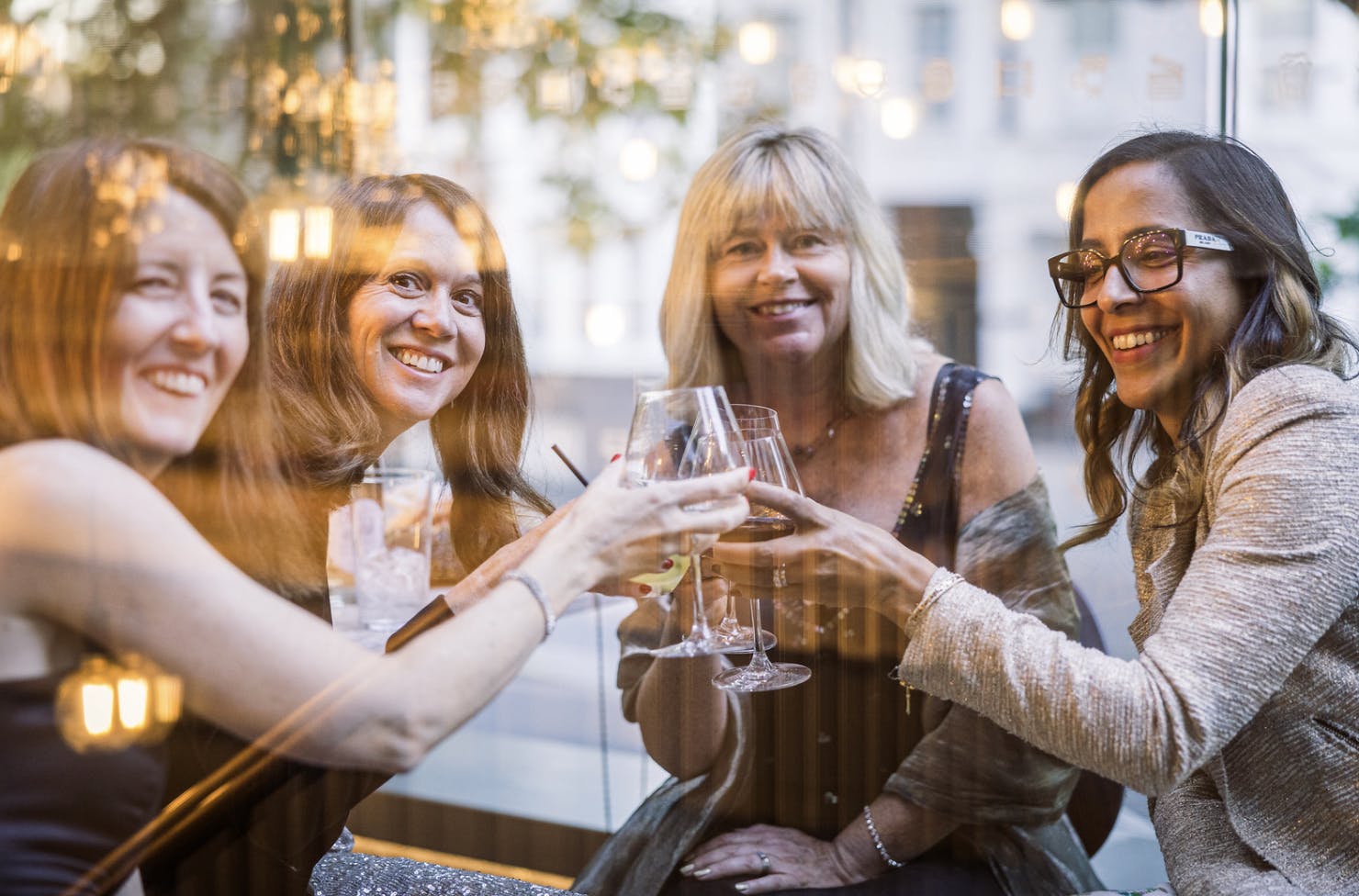 Smiling women cheers their glasses looking at the camera.