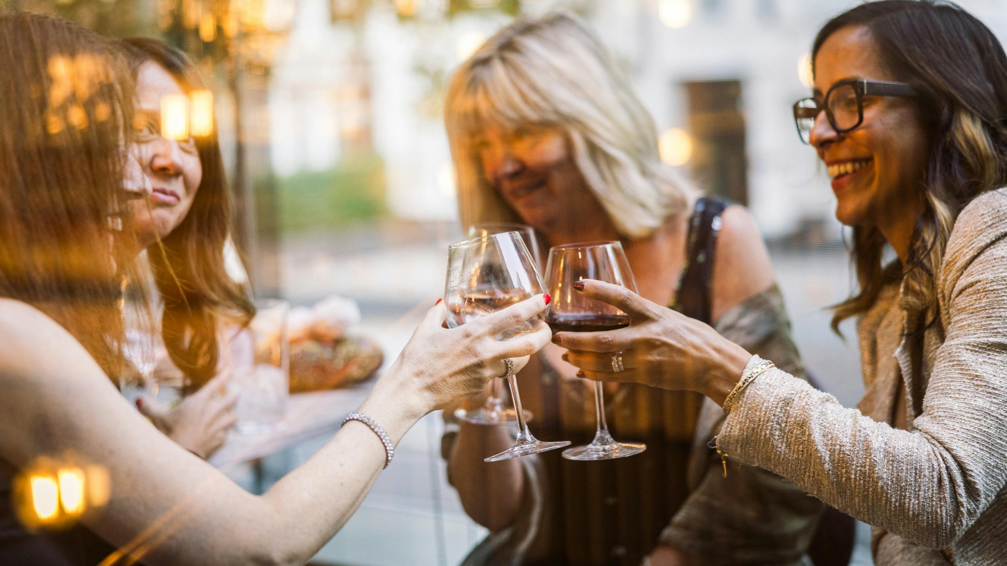 Smiling women cheers glasses of wine in the cinema's terrace.