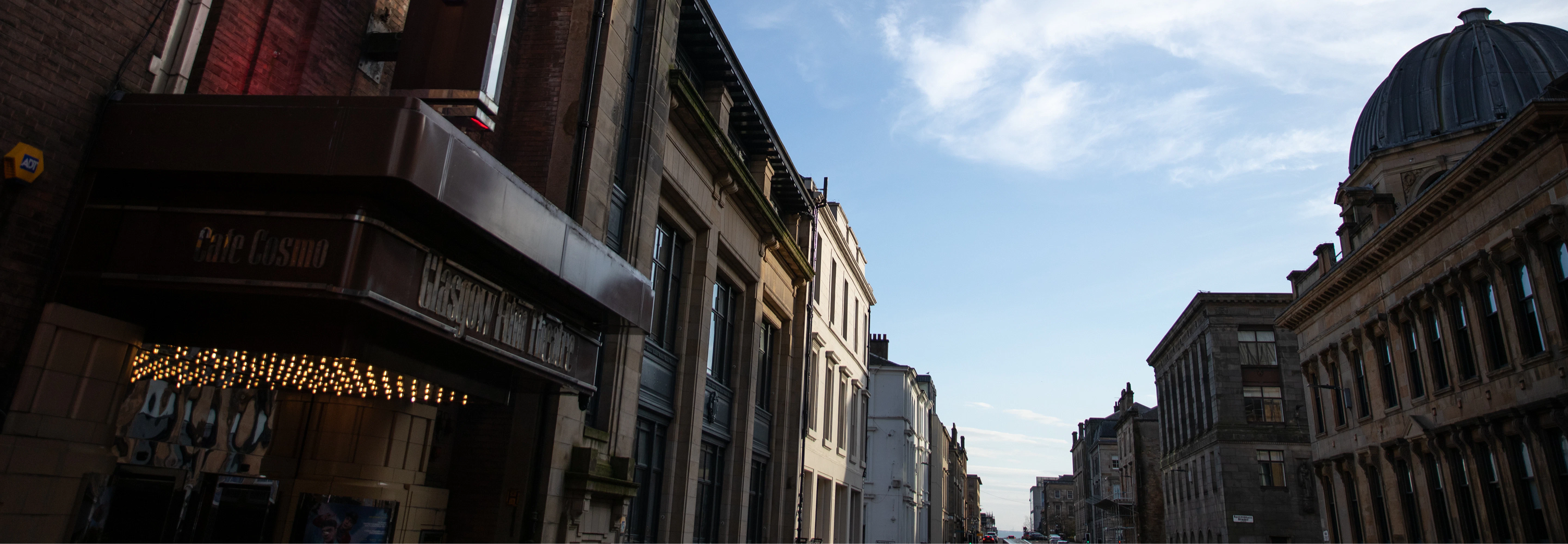Image of the Glasgow Film Theatre building at night with a blue sky and a large crowd gathered outside for an event