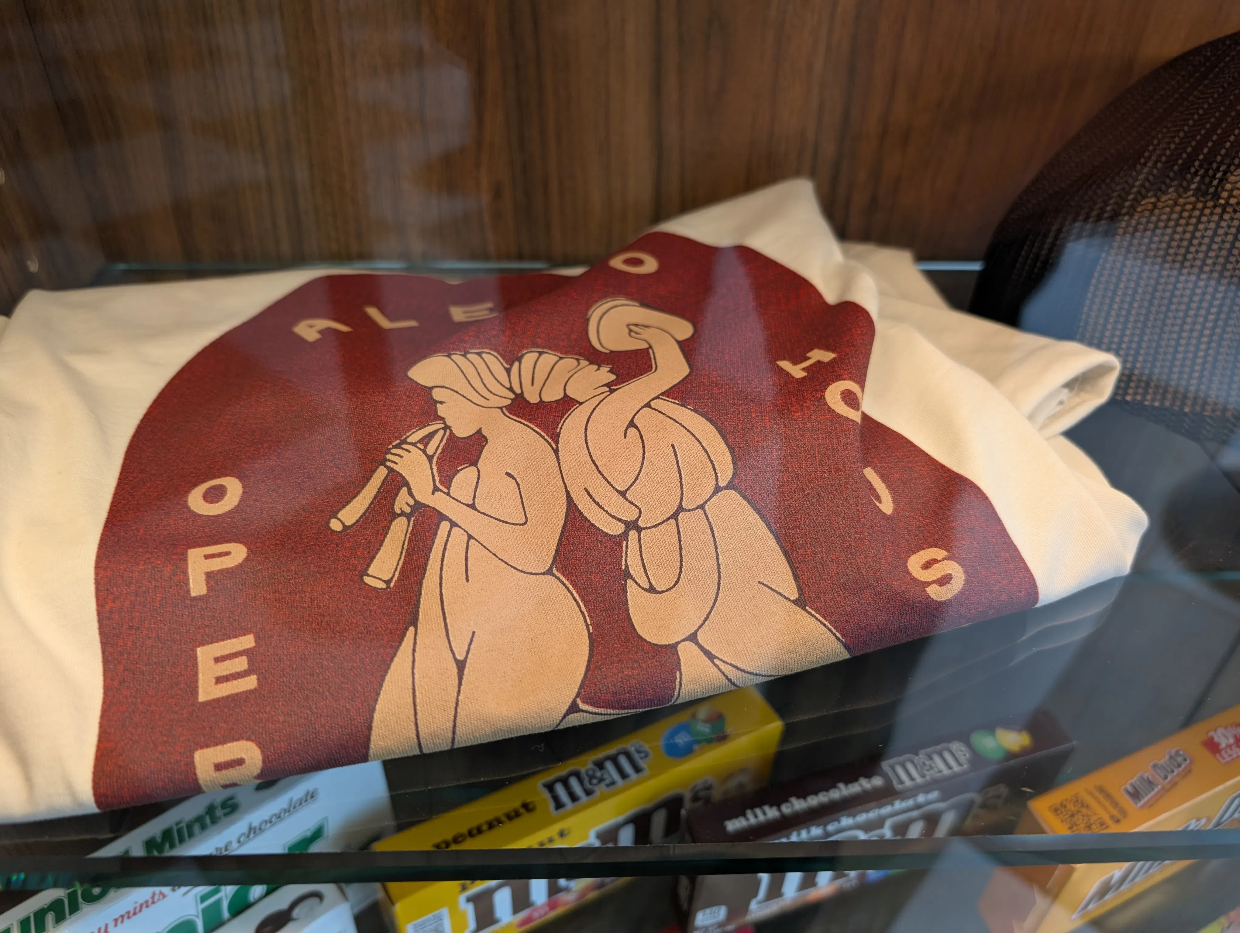 an off-white t-shirt with a burgundy and gold logo design containing the words Aledo Opera House and two dancing muses