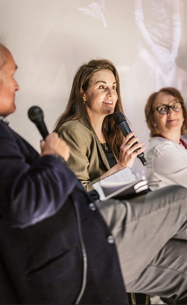 Michelle Dockery smiles while talking into a mic on stage.