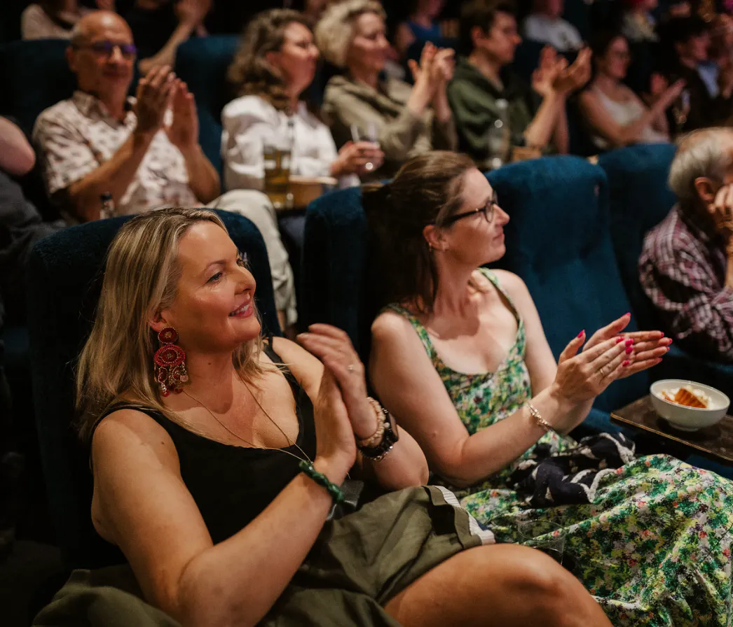 A screen of people in an audience smiling.