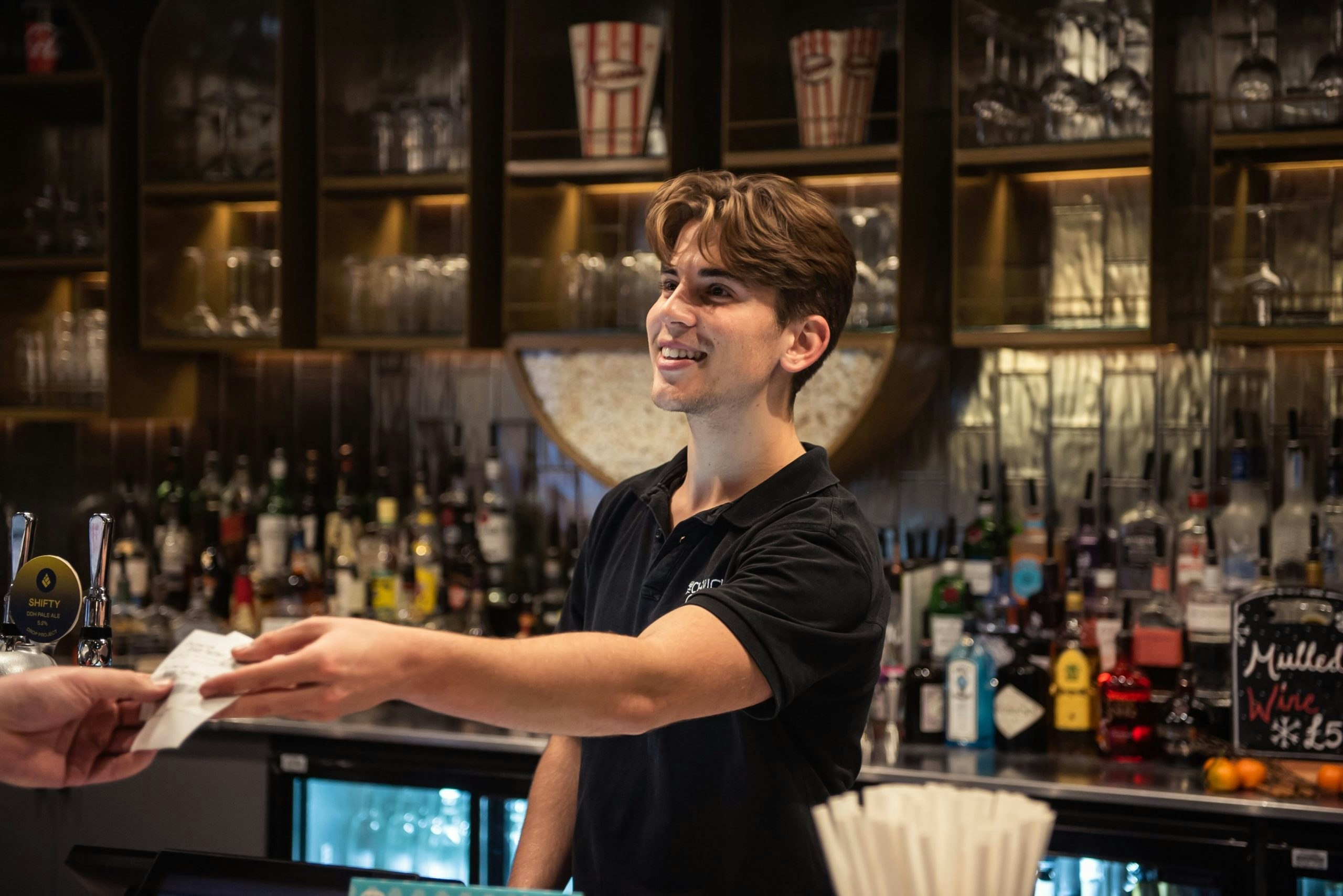A smiling member of staff hands over a ticket to a customer.
