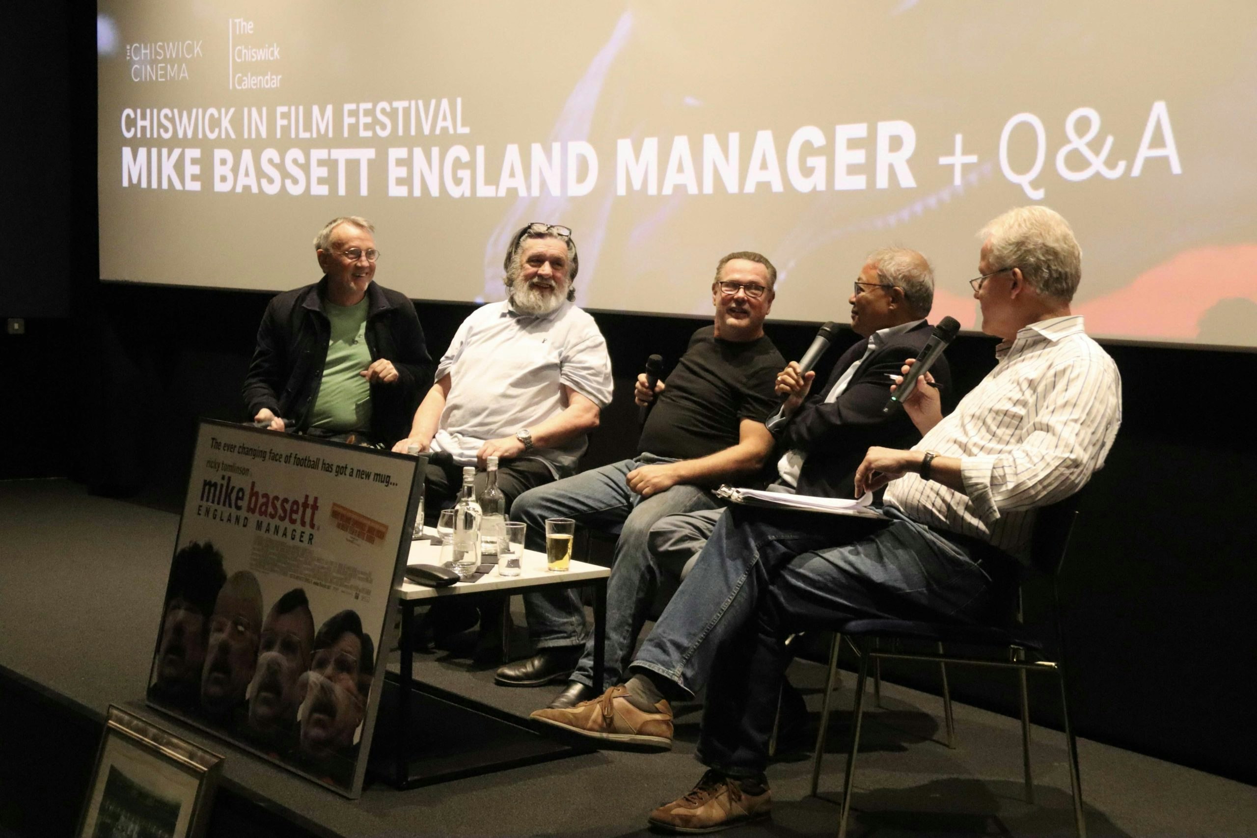 Ricky Tomlinson and other smiling guests talk about Mike Bassett England Manager on stage.