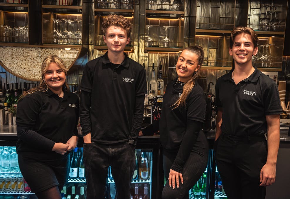 Four members of staff smile behind the bar at the cinema.
