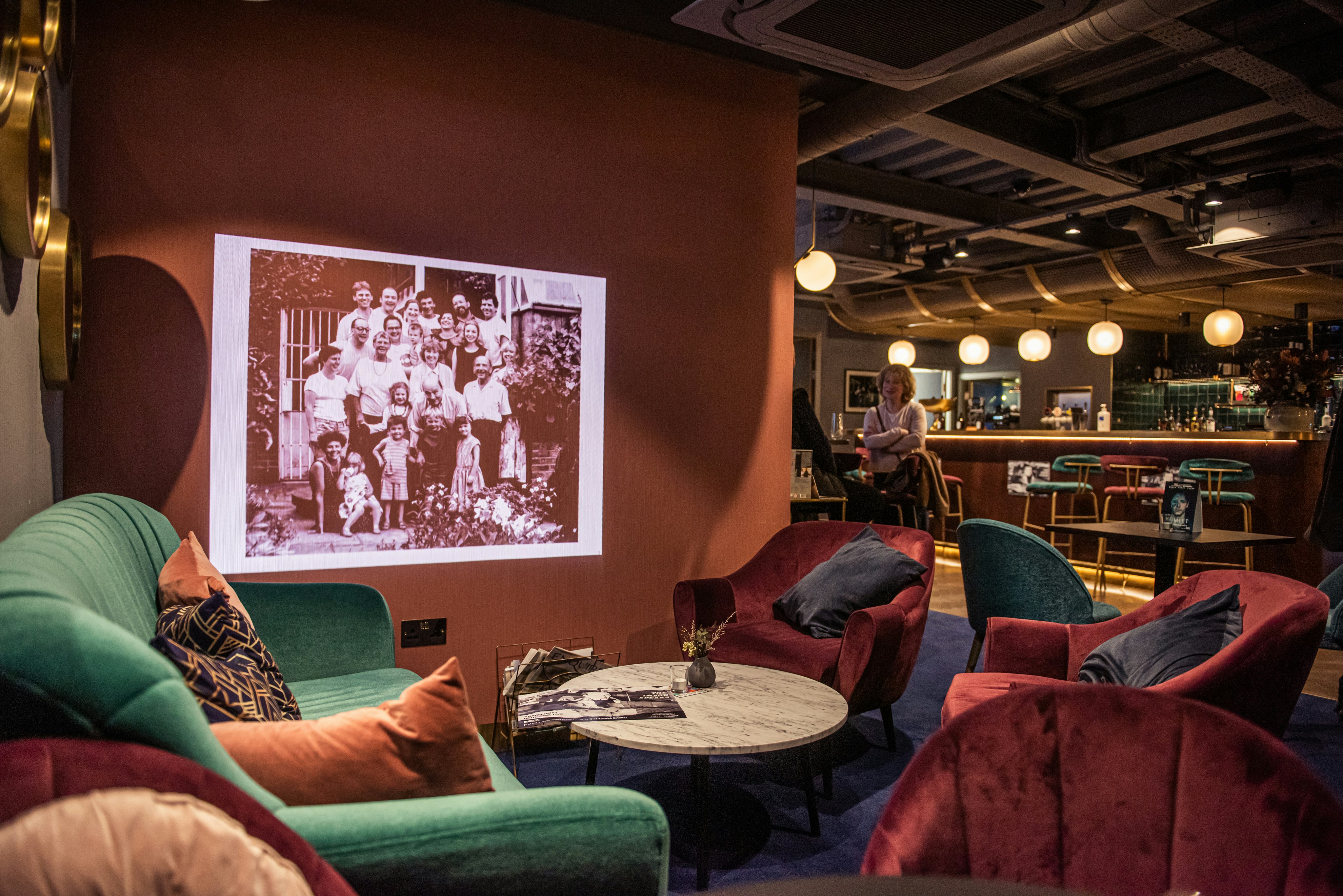 The cosy Lounge features sofas, arm chairs and a mini projector showing stills on a pink wall.