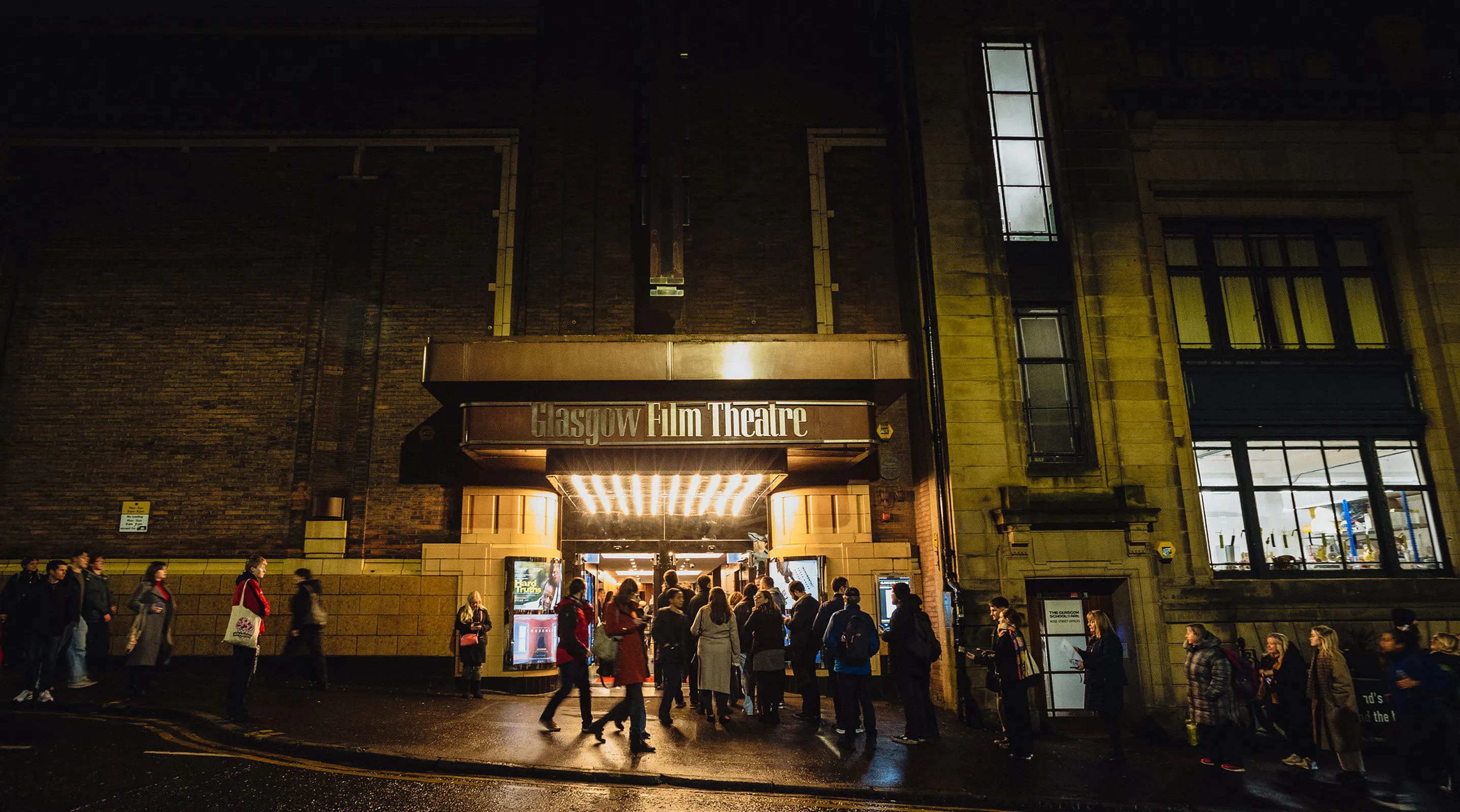 The exterior of Glasgow Film Theatre at night with people gathered outside