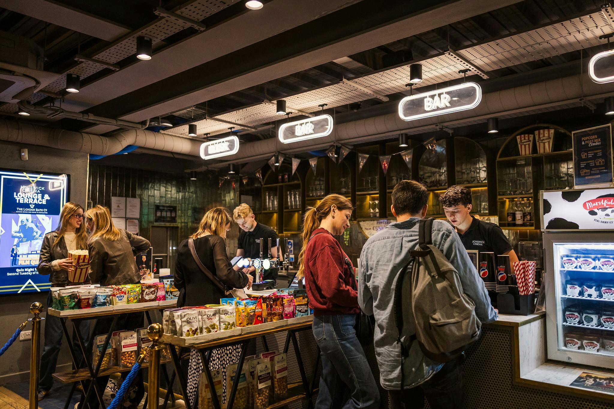 The Chiswick Cinema main bar with customers buying from a range of snacks.