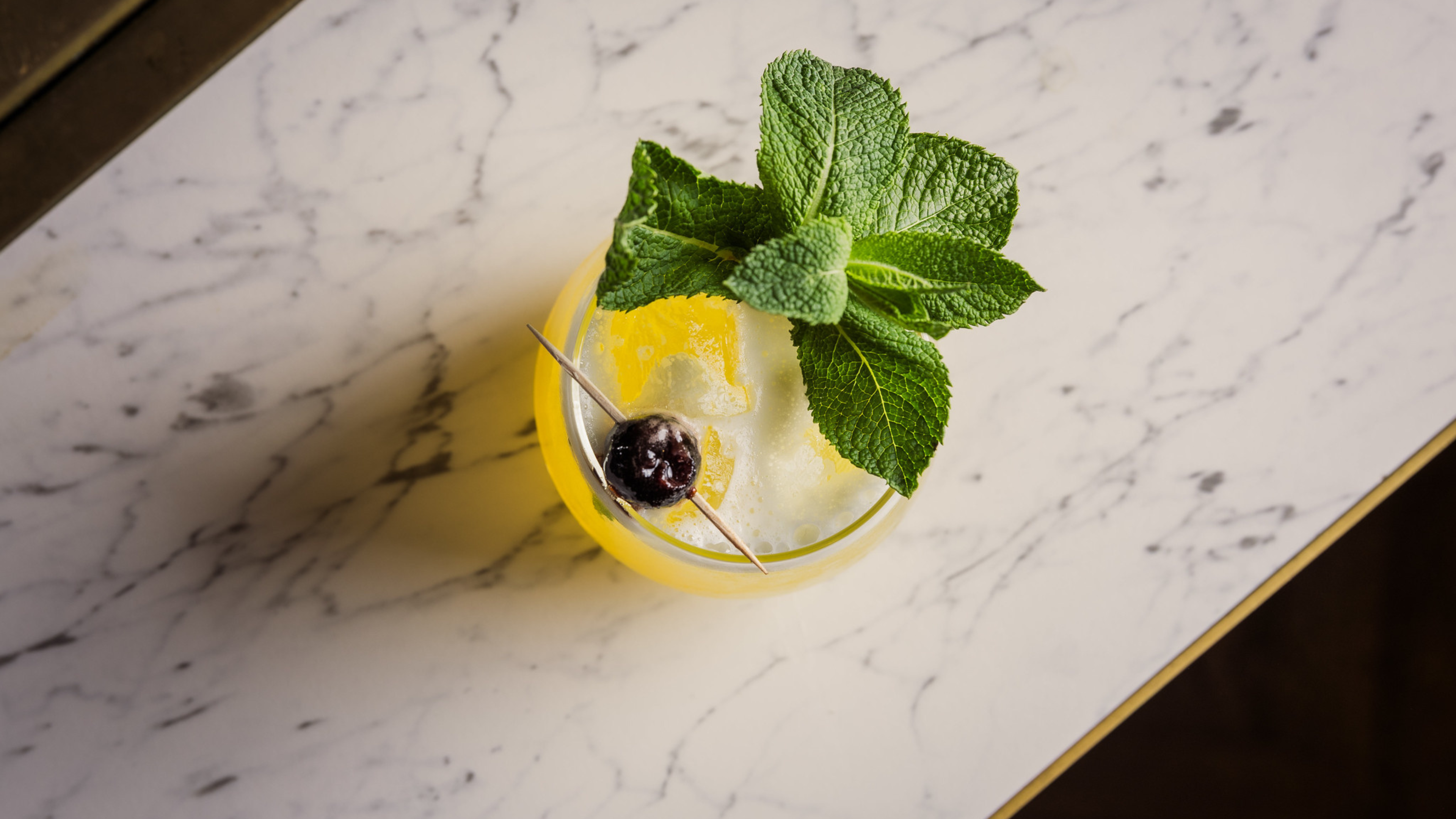 A mocktail sits atop the gold lined marble of the cinema bar.