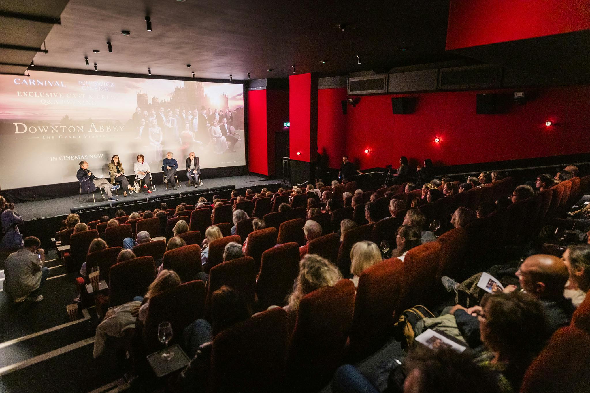 The Downton Abbey creative team speak to a full audience in a cinema screen.