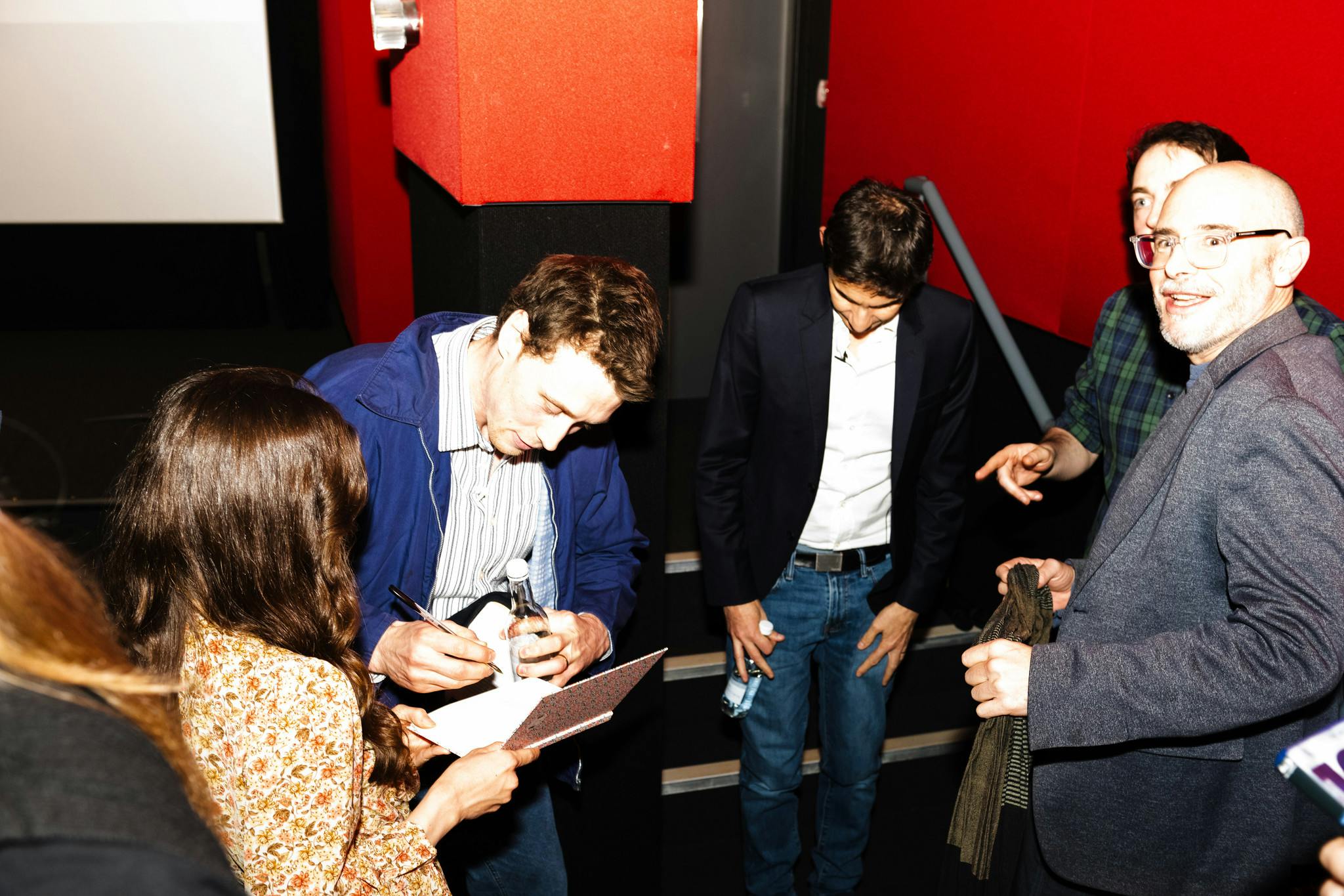 George MacKay signs autographs for fans in a cinema screen.