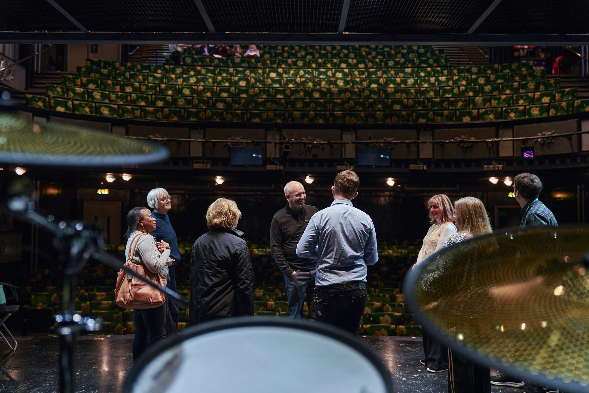 Members smile on stage during a private theatre tour in Central London.
